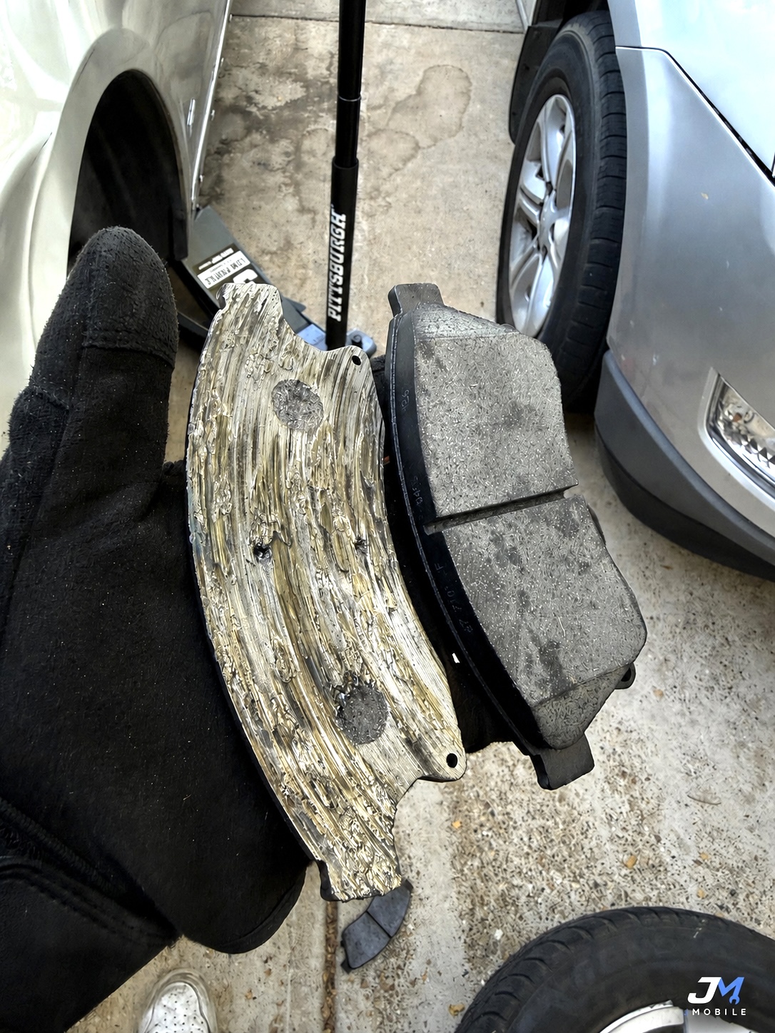 Worn brake rotor next to new brake pads for a 2013 Chevrolet Malibu